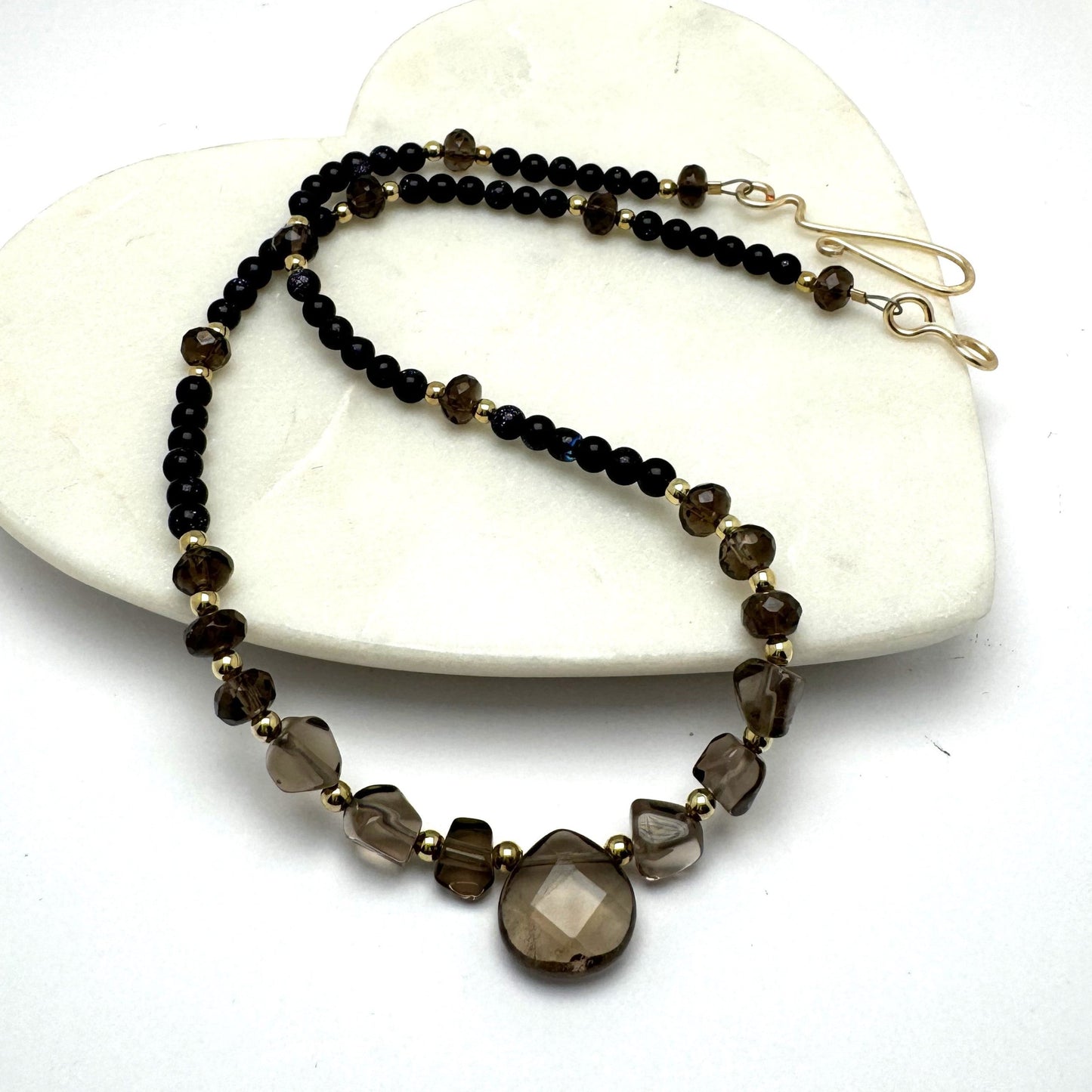 A handcrafted 17.5-inch necklace featuring polished black agate and smoky quartz beads for a sleek, versatile look. Designed for effortless day-to-night styling, this refined piece is finished with a signature handmade hook closure. A modern yet timeless accessory by Lacey & Bohème, perfect for any occasion. Handmade in Canada.