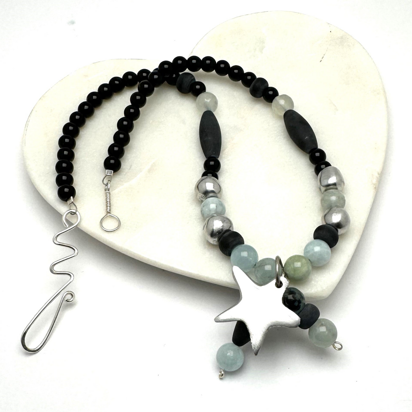 A handcrafted 18-inch necklace featuring a mix of black jasper, aquamarine, and aluminum beads, accented with a charming star pendant. Finished with a signature handmade hook clasp, this unique piece blends natural stones with modern materials for a versatile, stylish look. Handmade with care by Lacey & Bohème in Canada.