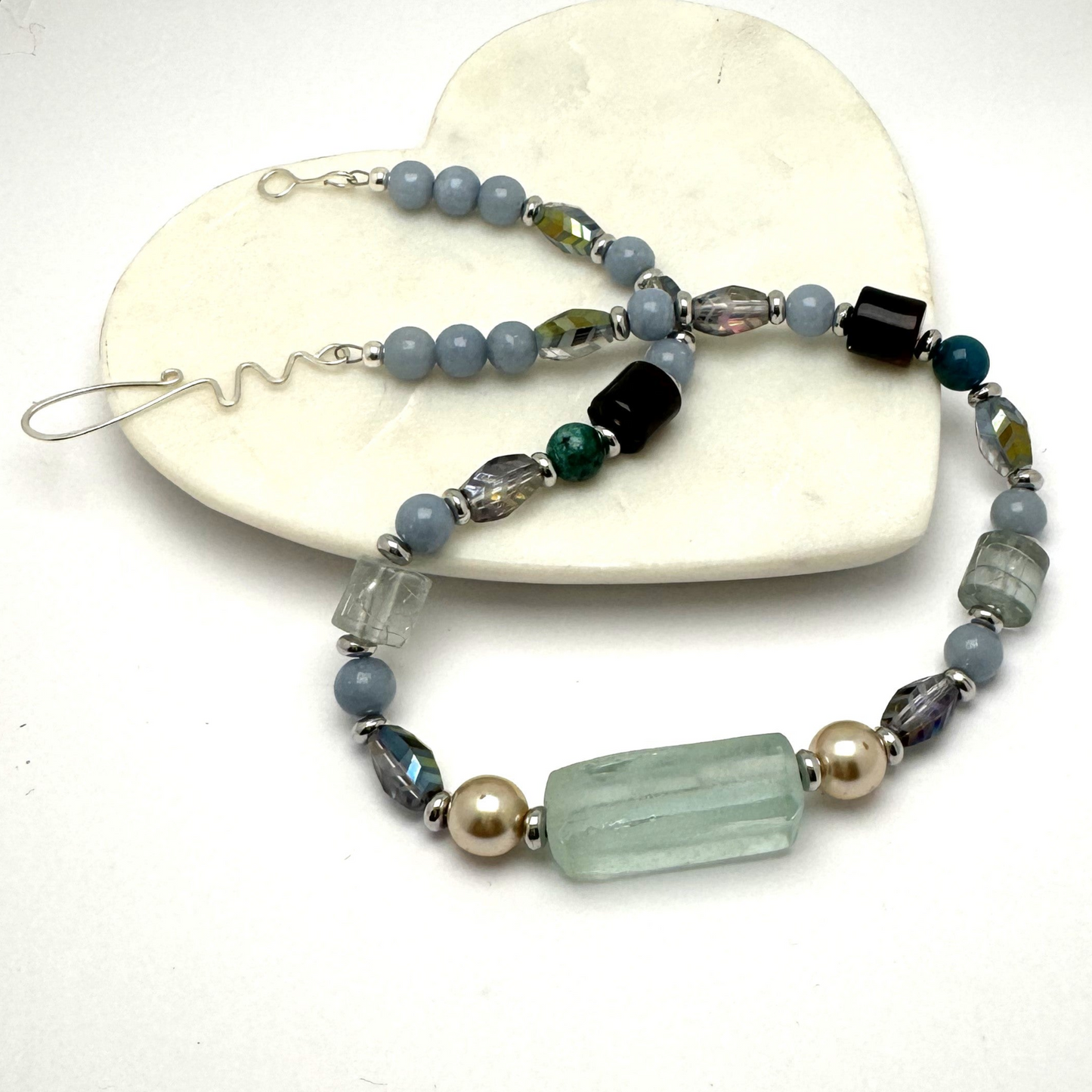 A chunky handmade statement necklace featuring mixed blue stones, including Angelite, Quartz, and Agate, with silver-tone accents and a signature hook clasp. Perfect for pairing with cozy sweaters, this modern and chic piece transitions effortlessly from casual to dressy occasions. Handmade by Lacey & Bohème in Canada.