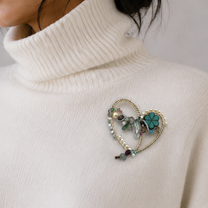 Woman wearing a white turtleneck sweater with a decorative brooch on a plain background