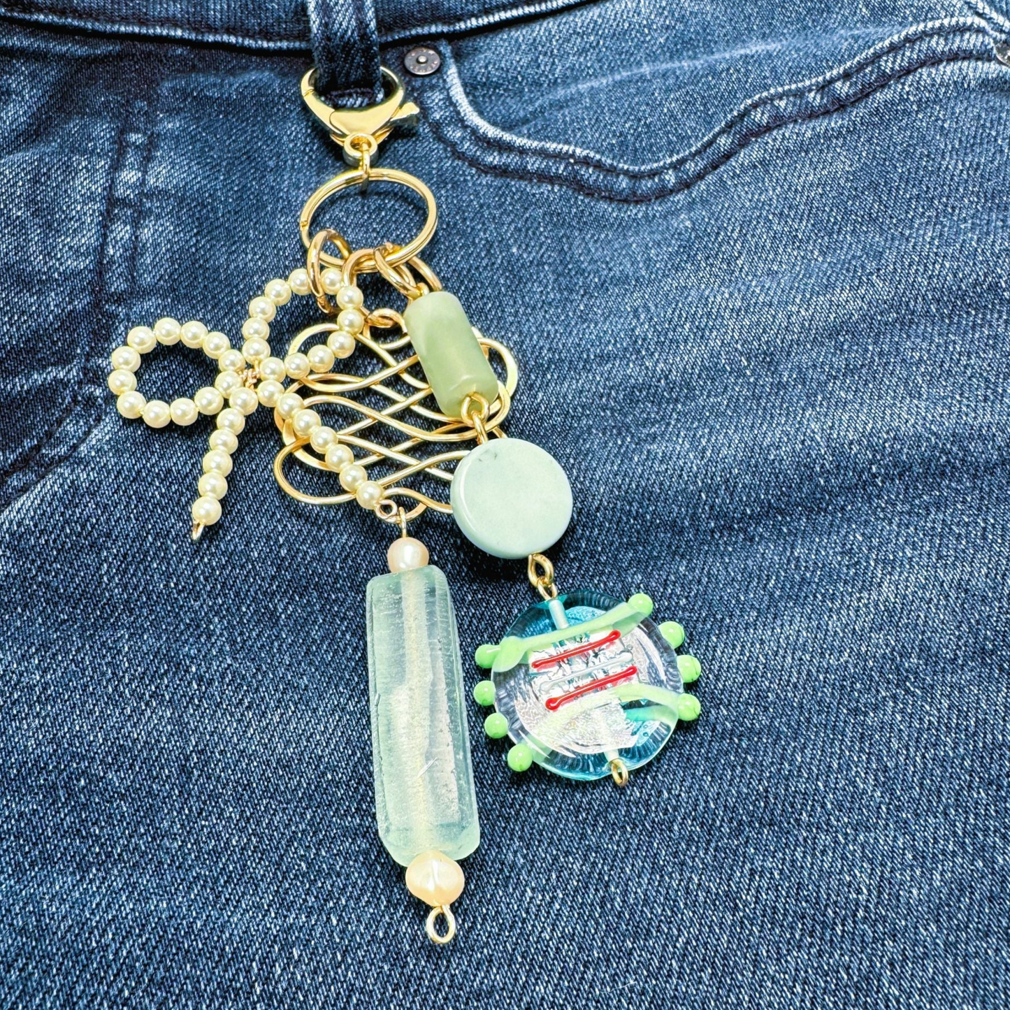 Accessory for Jeans. Clip this handmade accessory to jean loops, purses or backpacks. Made with a pearl bow, unique glass beads and forged wire.