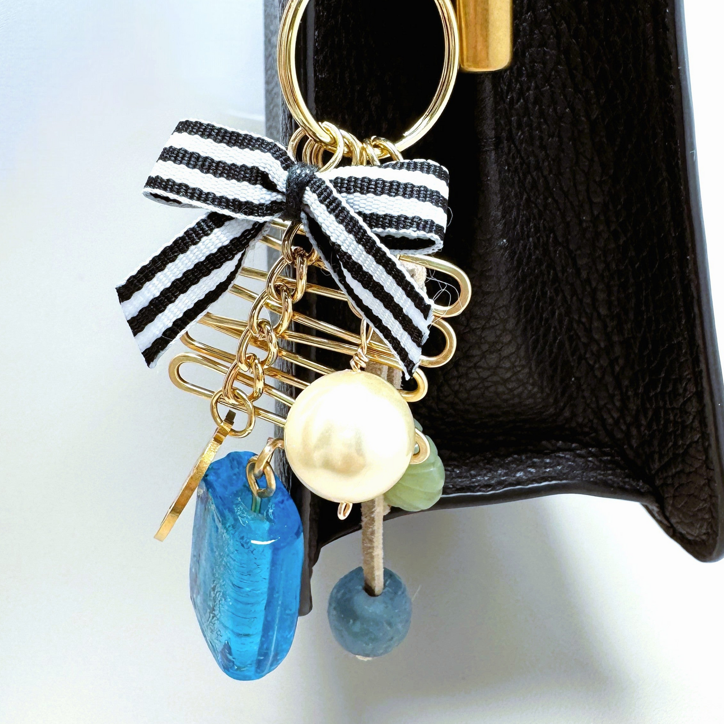 Handmade purse charm featuring a blue glass bead, large faux pearl, Tree of Life charm, serpentine oval bead, sea glass accent, and hand-forged wire decoration. Clips onto purses, backpacks, jeans loops, or belts.