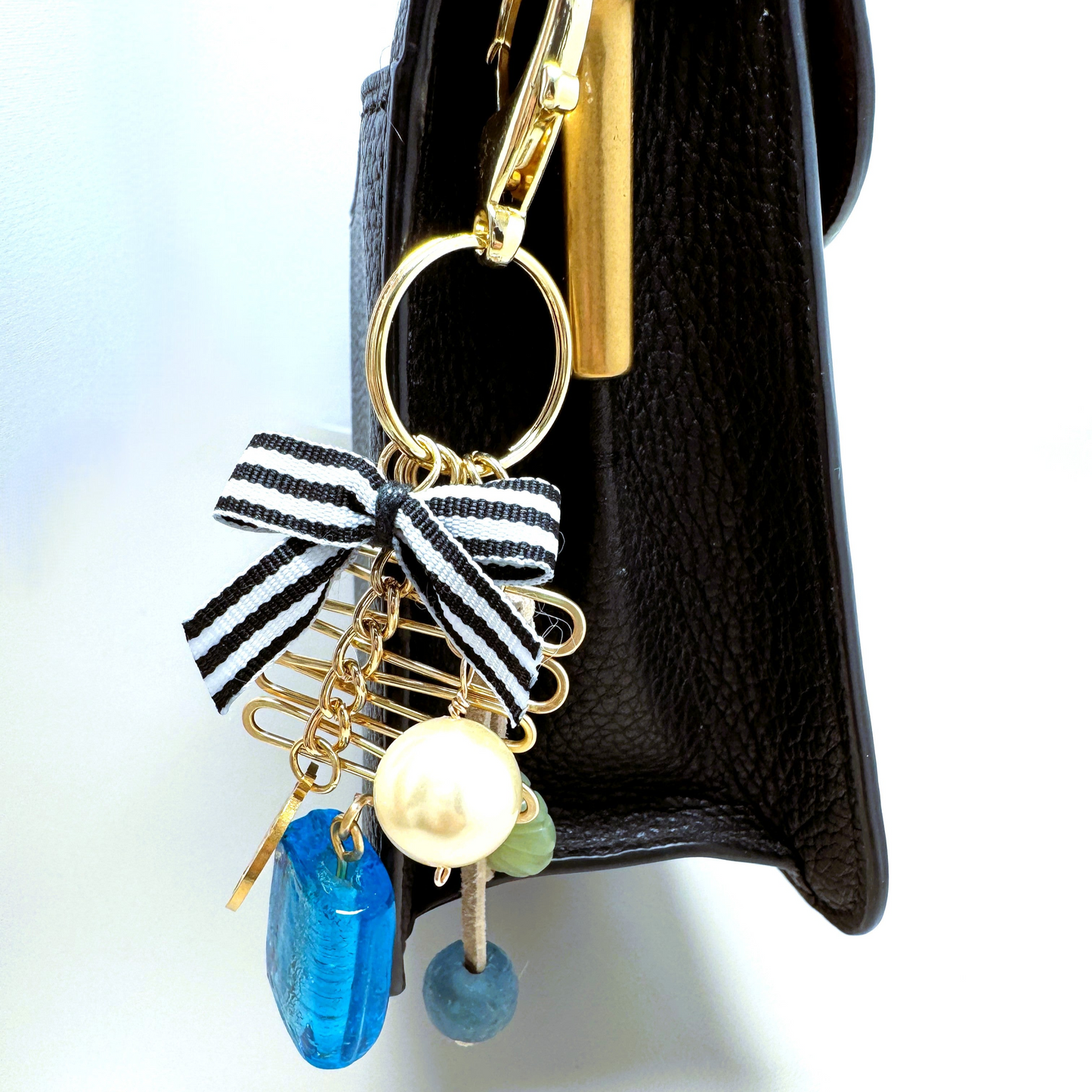 Handmade purse charm featuring a blue glass bead, large faux pearl, Tree of Life charm, serpentine oval bead, sea glass accent, and hand-forged wire decoration. Clips onto purses, backpacks, jeans loops, or belts.