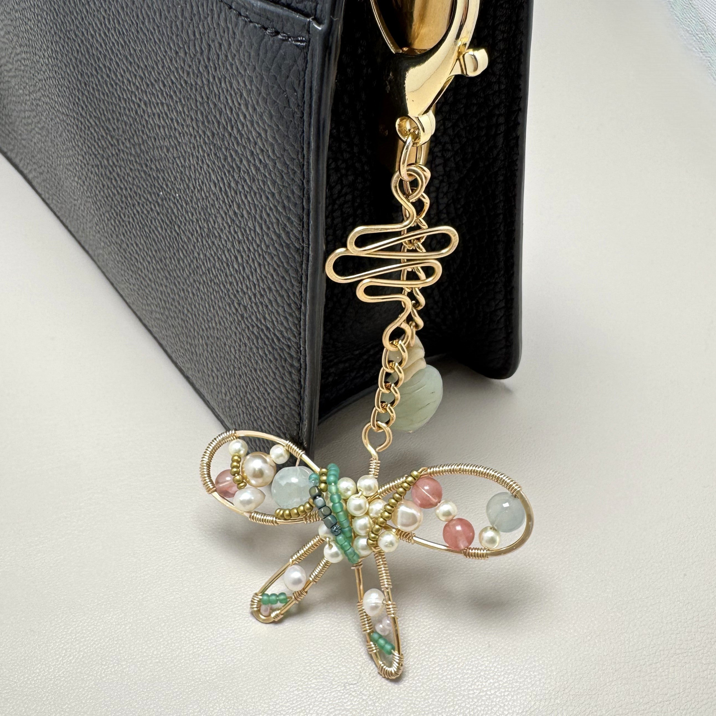 Handmade stylized butterfly purse charm with forged wire, glass, and vintage beads, clipped to a handbag with lobster clasp.