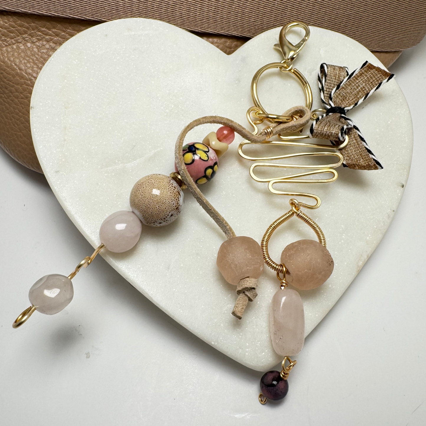 Handmade purse charm with rose quartz, sea glass, ceramic beads, gold-tone wire, and a detachable bow. Clips to bags, belts, and jean loops.