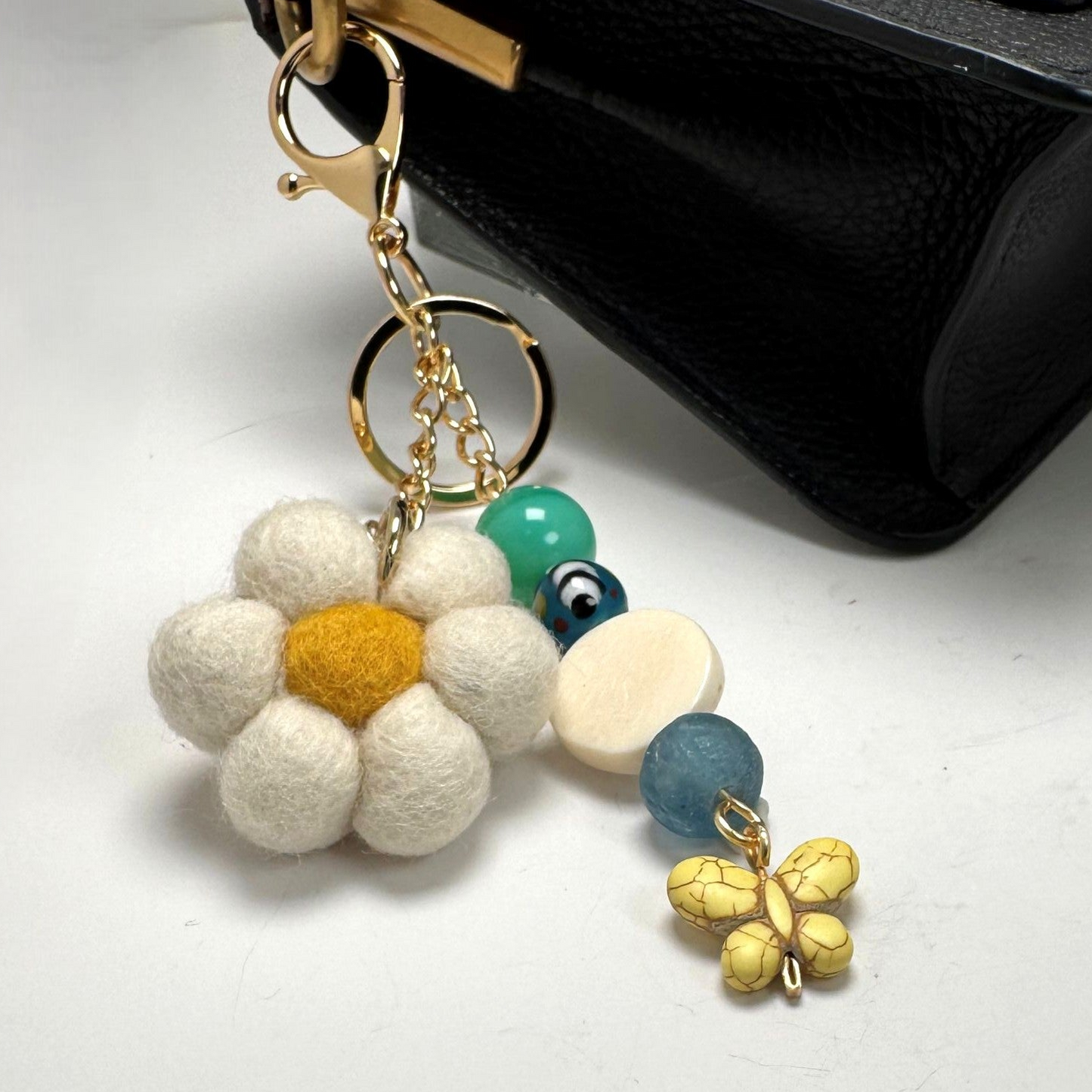 Handmade felted flower purse charm and keychain with vintage beads and sea glass, clipped to a canvas tote.