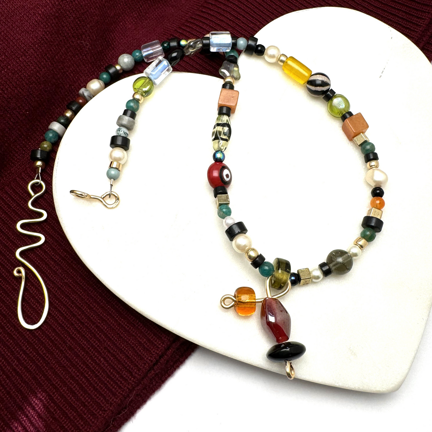 A handcrafted 18-inch necklace featuring a playful mix of decorative glass beads and natural stones in a vibrant array of colors and textures. Accented with gold-tone details, a unique handmade tie charm, and a secure handcrafted hook clasp, this lively piece adds a touch of artisanal charm to any outfit. Perfect for casual and chic styles alike. Handmade in Canada.