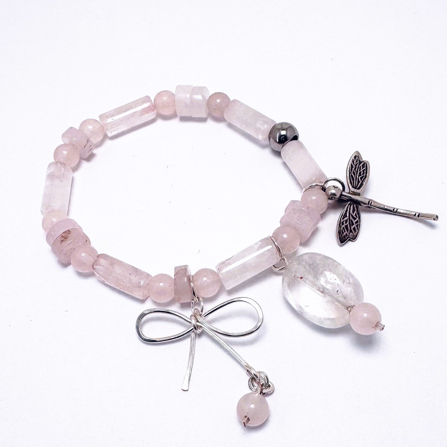 A delicate rose quartz bracelet featuring whimsical charms, perfect for stacking or wearing alone. Known as the "Love Stone," rose quartz is believed to open the heart to love and healing. Handmade in Canada.