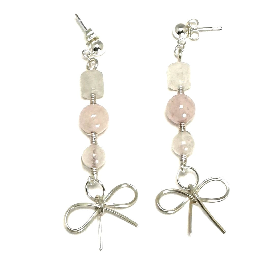 A pair of handcrafted rose quartz drop earrings featuring a delicate sterling silver bow accent and sterling silver ear posts. Elegant and feminine, measuring 2 inches (5 cm).