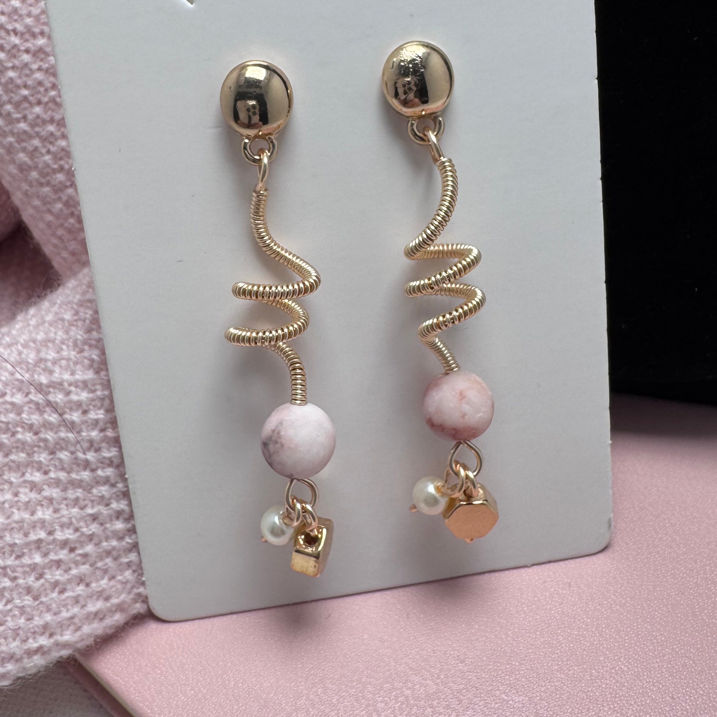 Gold-tone pierced stud earrings featuring a wrapped wire spiral design, accented with a lustrous pearl and sleek gold-tone hexagon charm. A lightweight, versatile blend of classic sophistication and modern elegance.