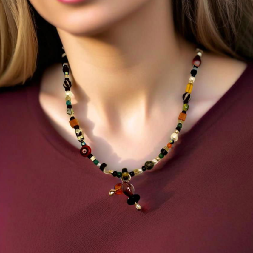A handcrafted 18-inch necklace featuring a playful mix of decorative glass beads and natural stones in a vibrant array of colors and textures. Accented with gold-tone details, a unique handmade tie charm, and a secure handcrafted hook clasp, this lively piece adds a touch of artisanal charm to any outfit. Designed by Lacey & Bohème, perfect for casual and chic styles alike. Handmade in Canada.