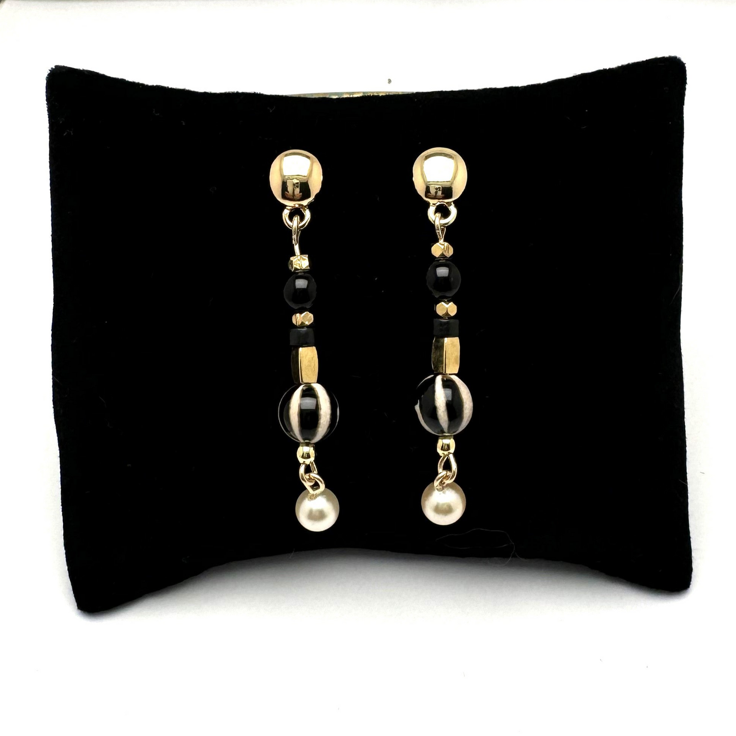 A pair of handcrafted 2-inch drop earrings featuring a mix of gold, black and pearl beads for a stylish, eclectic look. These lightweight earrings are perfect for adding a touch of individuality to any outfit. Handmade with care by Lacey & Bohème in Canada.