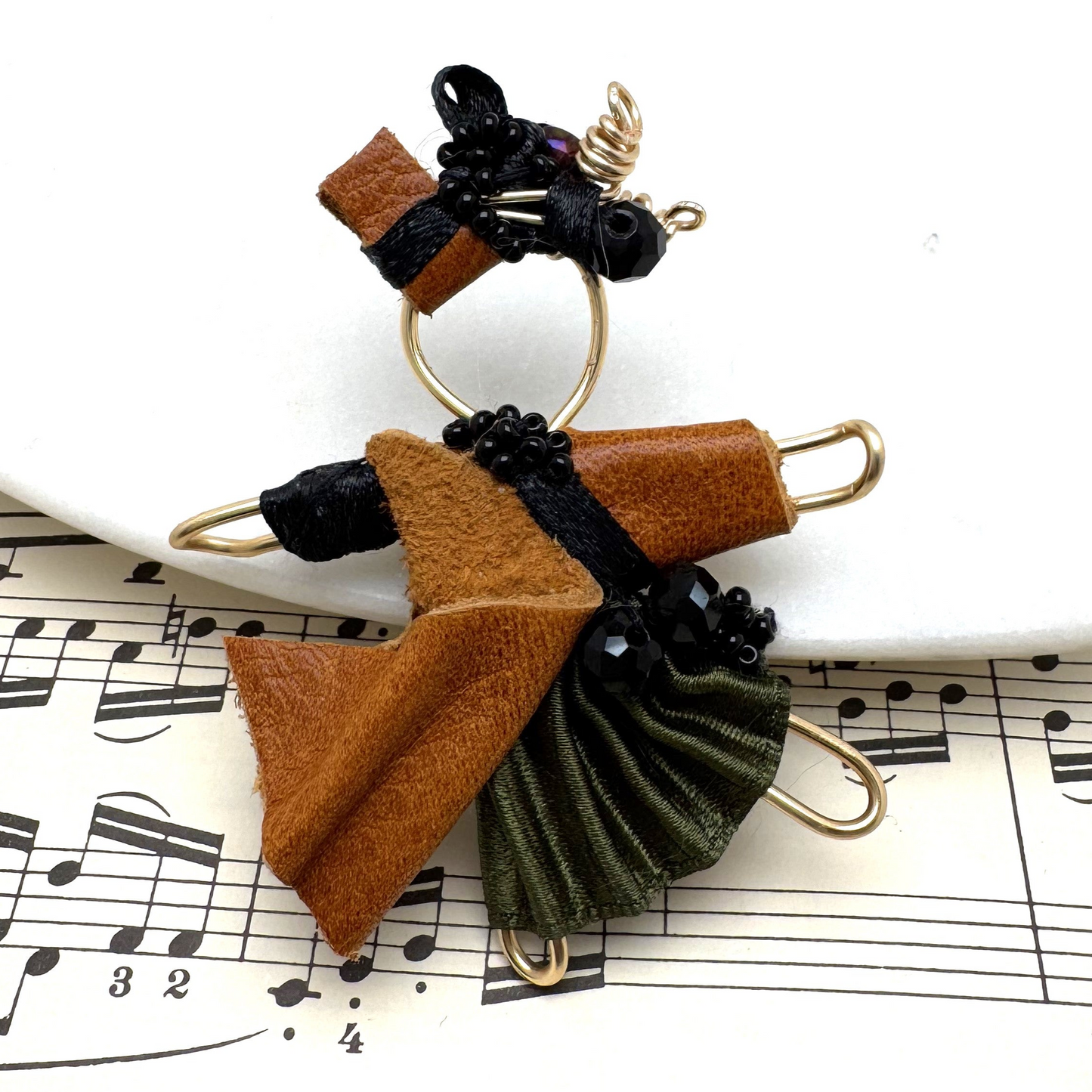 The Pixie Pin is a handcrafted brooch made from rich brown suede, recycled silk, beads, and wire, embodying strength, resilience, and the adventurous spirit of the pixie realm. Perfect for jackets, scarves, or bags