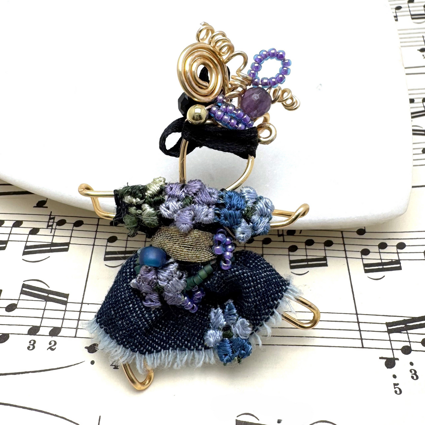 The Pixie Pin is a whimsical handmade brooch featuring denim with delicate embroidered flowers, capturing the playful and creative spirit of the pixie realm. A charming accessory for jackets, scarves, or bags.
