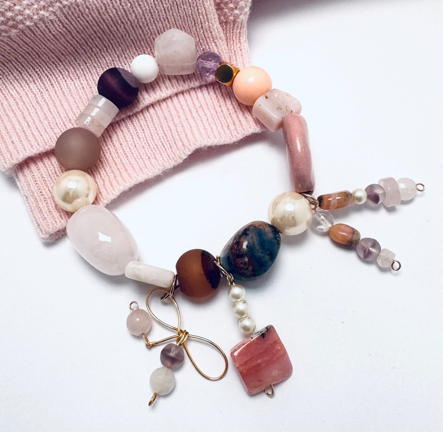A handcrafted bracelet featuring sodalite, pink opal, rose quartz, and agate in soft pink tones. Designed for stacking or wearing alone, this boho-inspired piece is believed to promote love, healing, and creativity. Handmade in Canada.