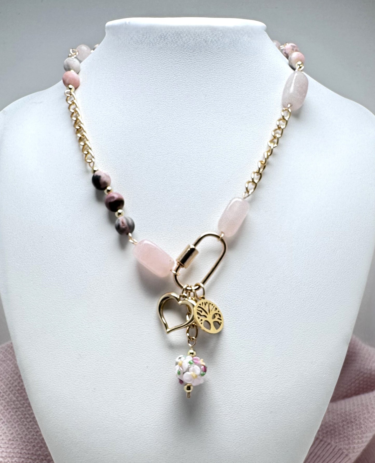 Asymmetrical rose quartz and gold chain necklace with carabiner focal point with heart, tree of life and floral lamp work charms.