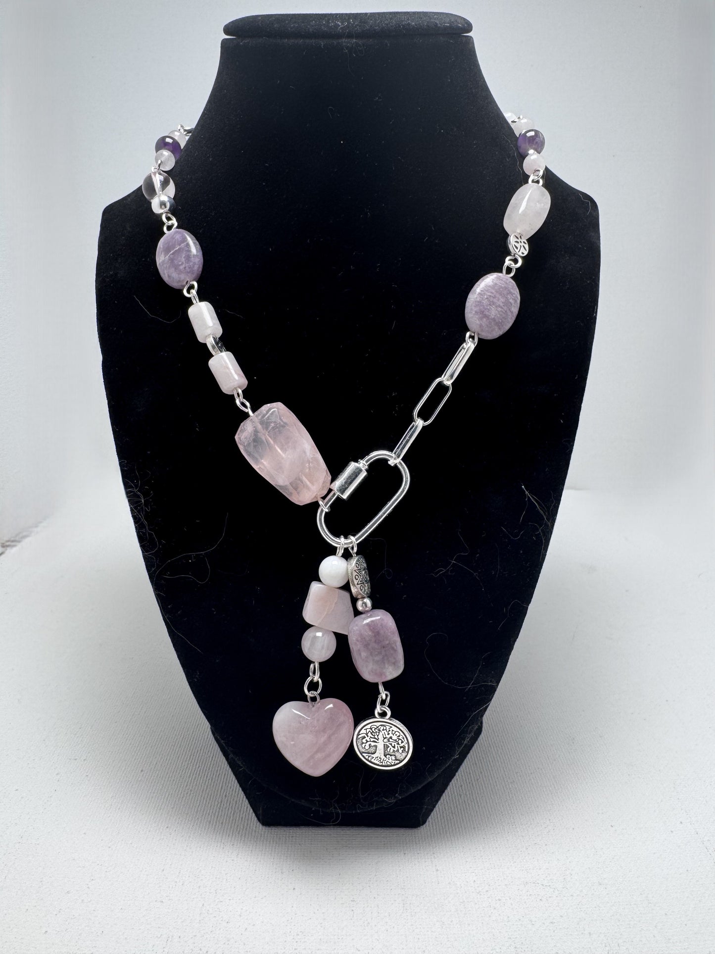 Bold 18-inch silver necklace featuring rose quartz, amethyst, and pink opal stones in an asymmetrical design. Dangled charms include a rose quartz heart with pink opal and an amethyst paired with a Tree of Life charm. A timeless, modern accessory perfect for day-to-night wear.