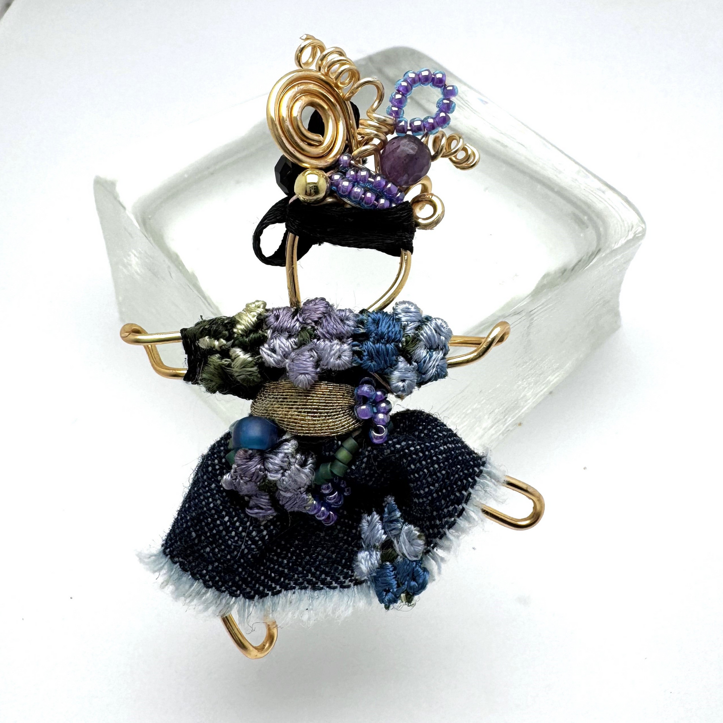 The Pixie Pin is a whimsical handmade brooch featuring denim with delicate embroidered flowers, capturing the playful and creative spirit of the pixie realm. A charming accessory for jackets, scarves, or bags.