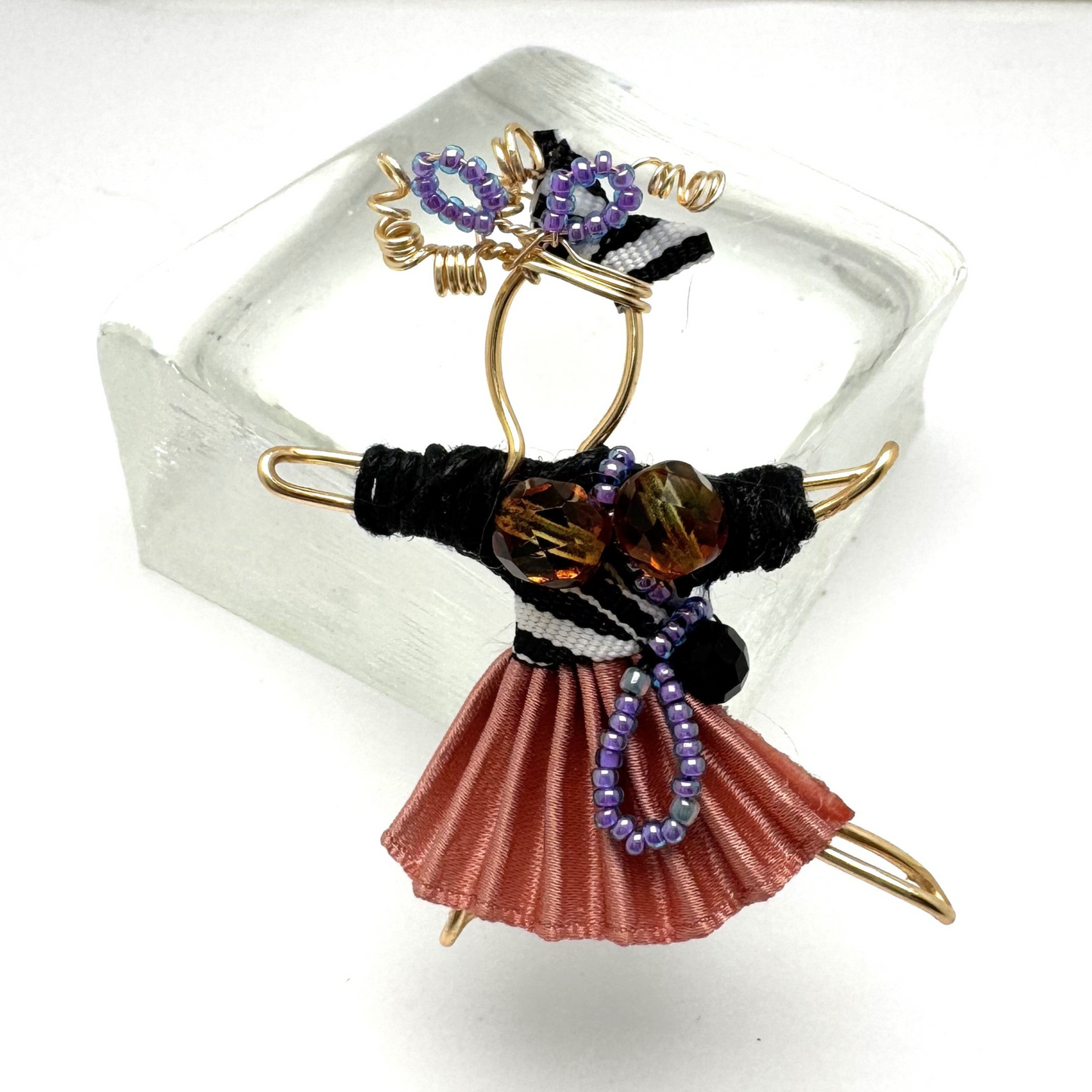 The Pixie Pin is a whimsical handmade brooch crafted from recycled silk, beads, ribbon, and wire, inspired by the playful spirit of pixies. Perfect for adding a touch of enchantment to jackets, scarves, or bags.