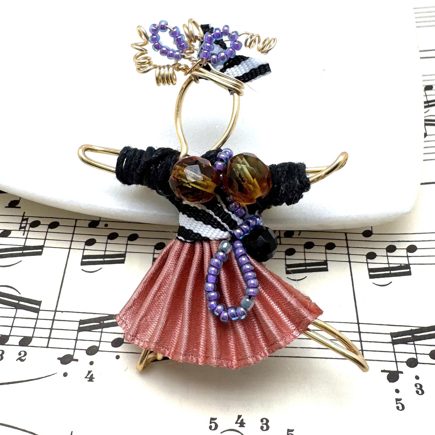 The Pixie Pin is a whimsical handmade brooch crafted from recycled silk, beads, ribbon, and wire, inspired by the playful spirit of pixies. Perfect for adding a touch of enchantment to jackets, scarves, or bags.
