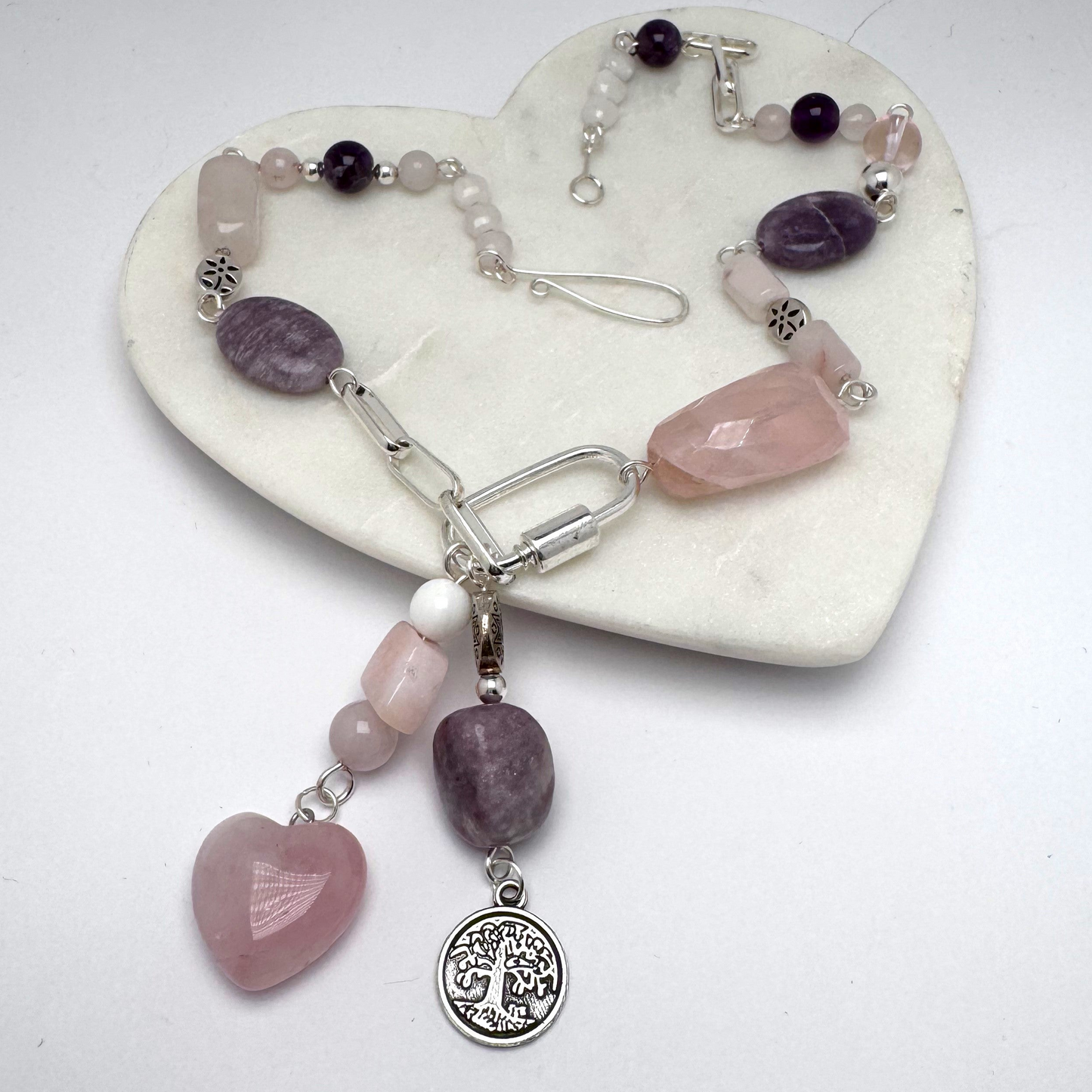 Bold 18-inch silver necklace featuring rose quartz, amethyst, and pink opal stones in an asymmetrical design. Dangled charms include a rose quartz heart with pink opal and an amethyst paired with a Tree of Life charm. A timeless, modern accessory perfect for day-to-night wear.