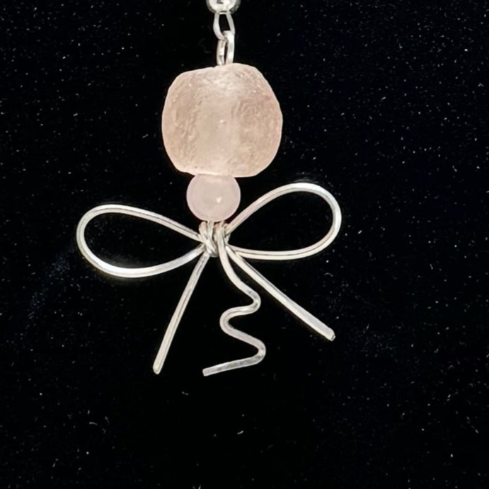 The Blush Bloom Y Necklace is a delicate, handcrafted piece featuring rose quartz, pink opal, sea glass, a floral lamp work bead, and a recycled aluminum heart. Designed with two Y-shaped pendants for a layered look, this 17.5-inch necklace embodies romance and sustainable elegance. Handmade in Canada.