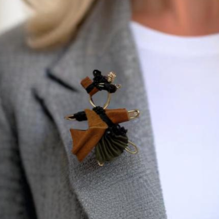 The Pixie Pin is a handcrafted brooch made from rich brown suede, recycled silk, beads, and wire, embodying strength, resilience, and the adventurous spirit of the pixie realm. Perfect for jackets, scarves, or bags