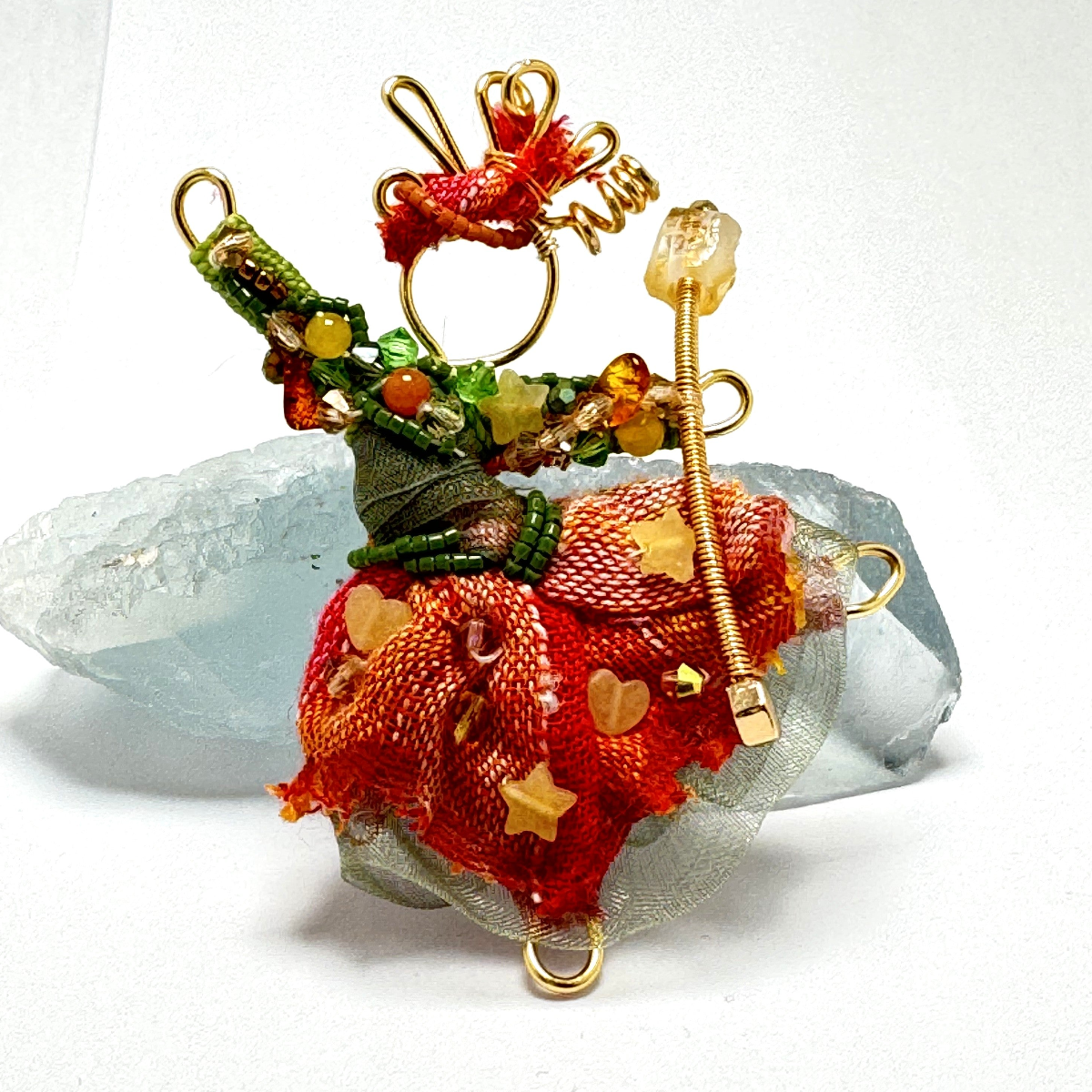 The Pixie Pin is a whimsical handmade brooch crafted from recycled silk, beads, ribbon, and wire, inspired by the playful spirit of pixies. Perfect for adding a touch of enchantment to jackets, scarves, or bags.