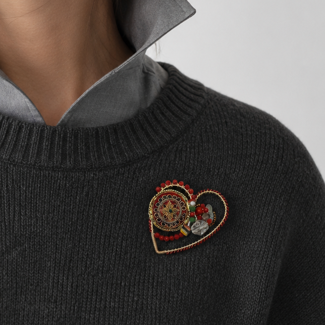 Woman wearing a dark sweater with a heart-shaped brooch on a light gray background