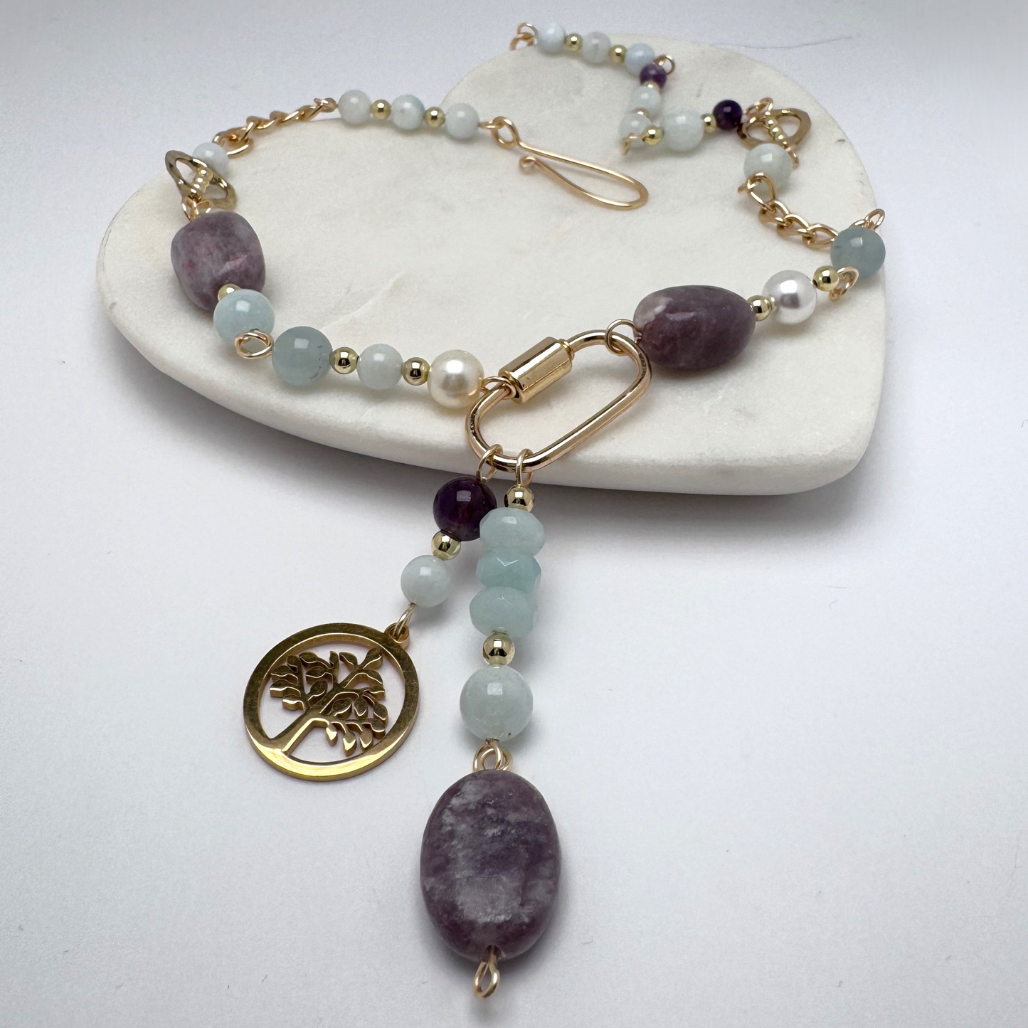 Bold 18-inch necklace featuring aquamarine, amethyst, and quartz stones on a gold chain. Highlighted with a gold carabiner, Tree of Life charm, and polished amethyst stone. Finished with a handcrafted hook clasp for an edgy, sophisticated design.
