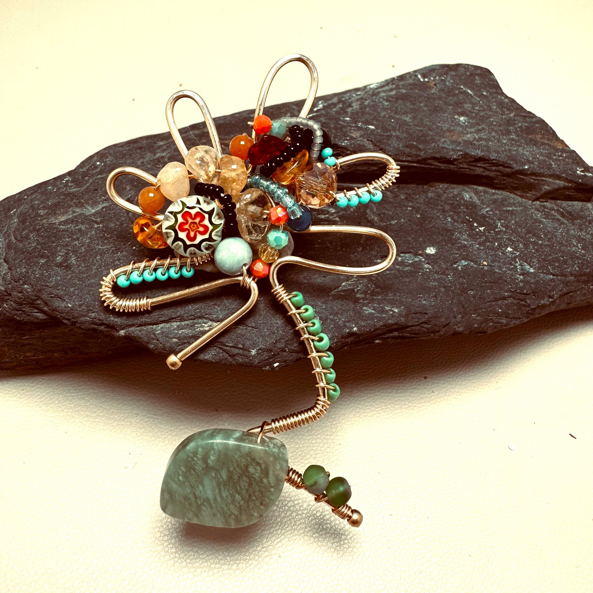 Decorative brooch with beads and gemstones on a stone surface