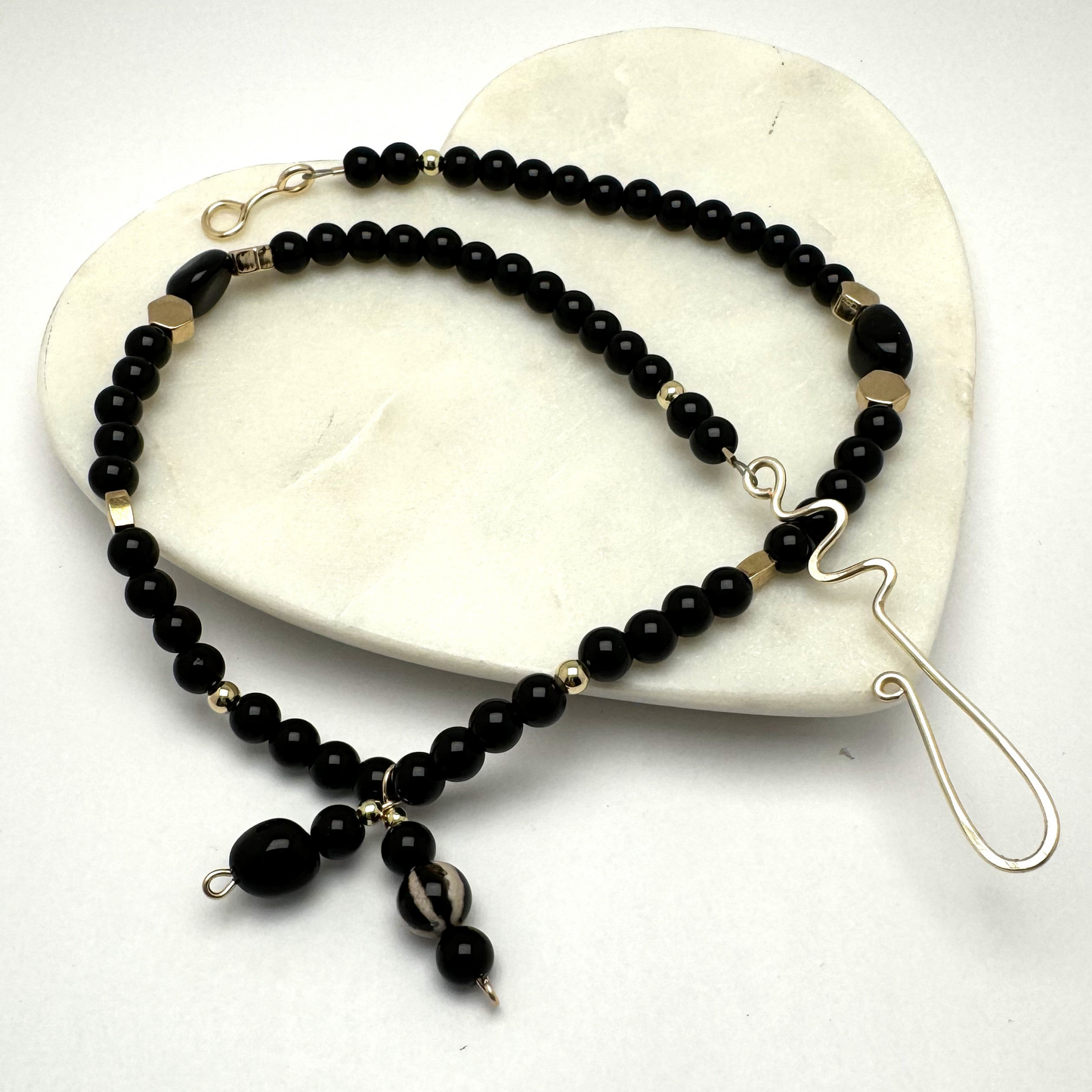 A handcrafted 18-inch black agate necklace featuring a stylish front-tie detail and a signature handmade hook clasp. Designed for versatility, this elegant piece is believed to dispel negative energy while promoting happiness and harmony. A timeless accessory by Lacey & Bohème, perfect for any occasion. Handmade in Canada.