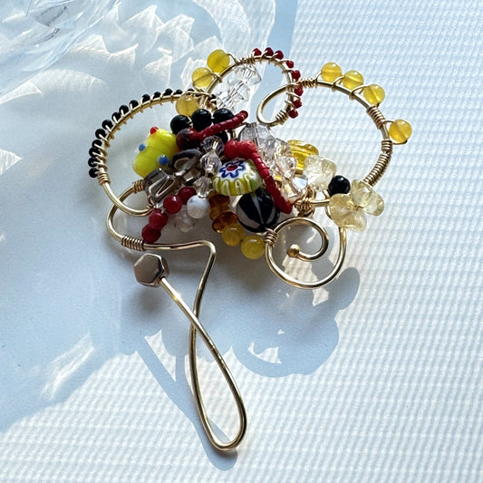 Decorative brooch with colorful beads on a light blue textured background