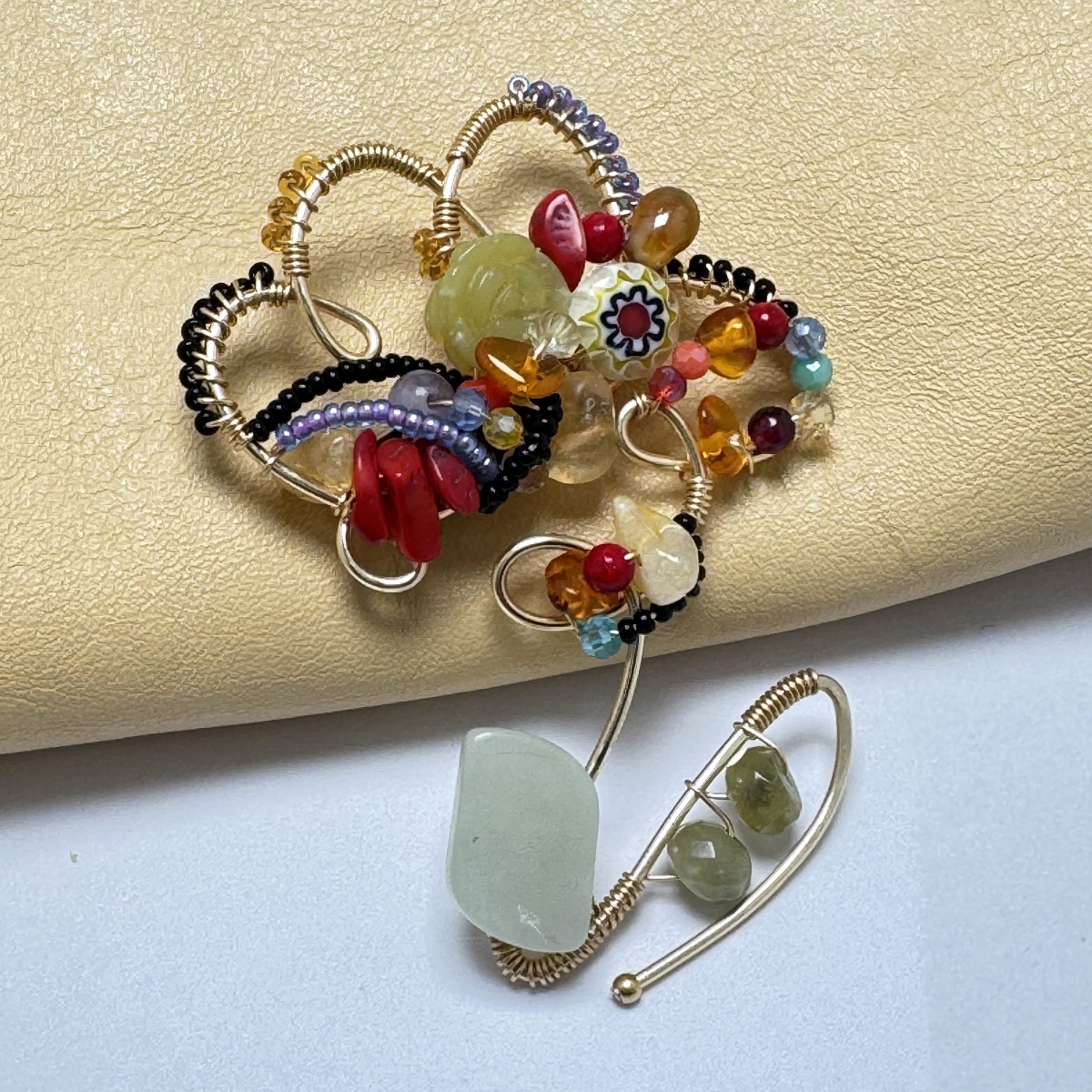 Colorful beaded brooch with gemstones on a light background