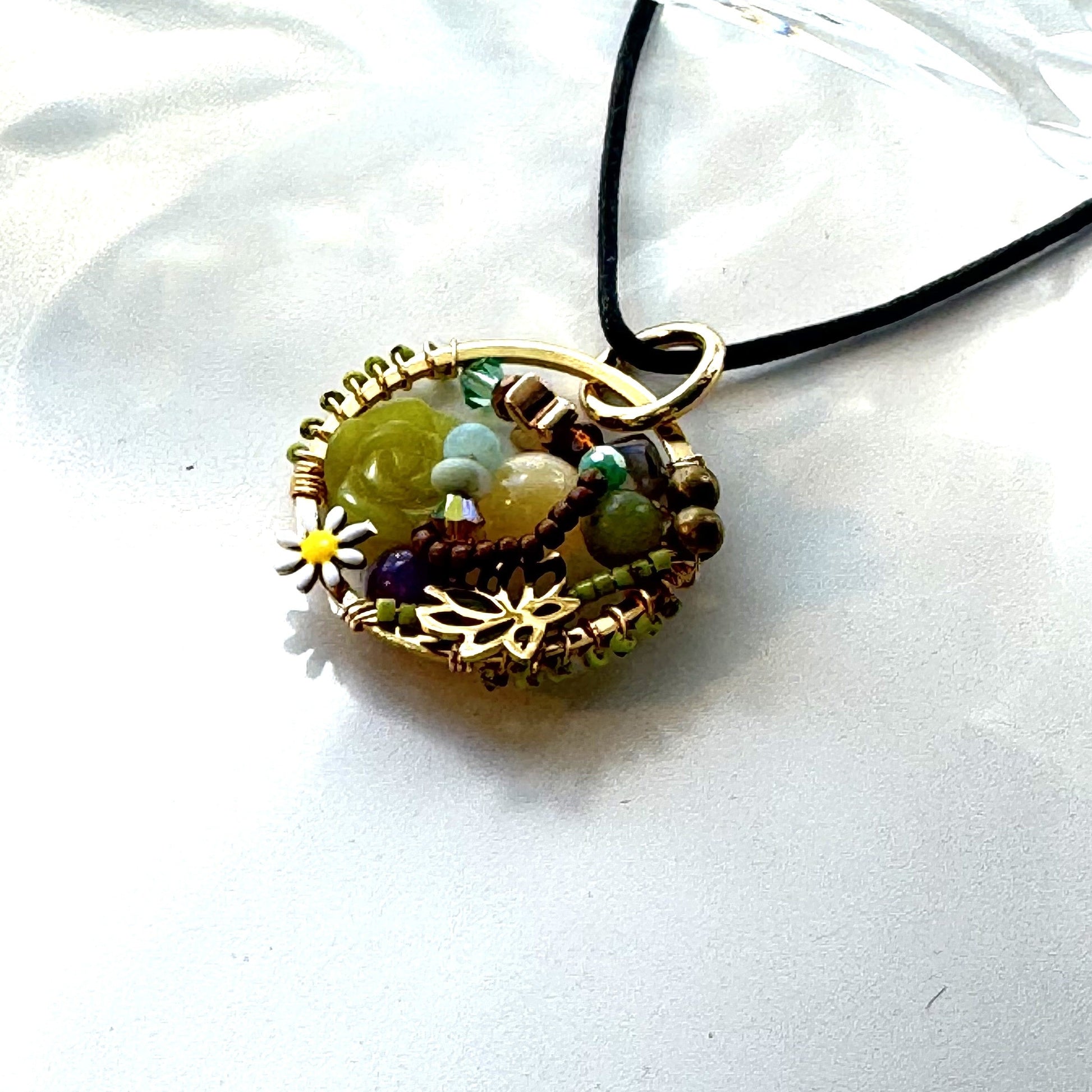 Necklace with a circular pendant featuring beads and a small yellow flower on a white background