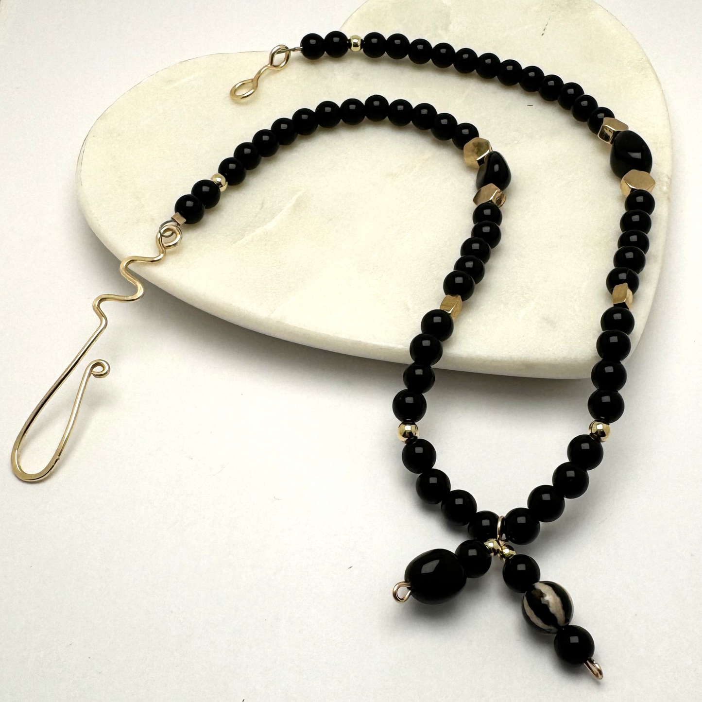 A handcrafted 18-inch black agate necklace featuring a stylish front-tie detail and a signature handmade hook clasp. Designed for versatility, this elegant piece is believed to dispel negative energy while promoting happiness and harmony. A timeless accessory by Lacey & Bohème, perfect for any occasion. Handmade in Canada.