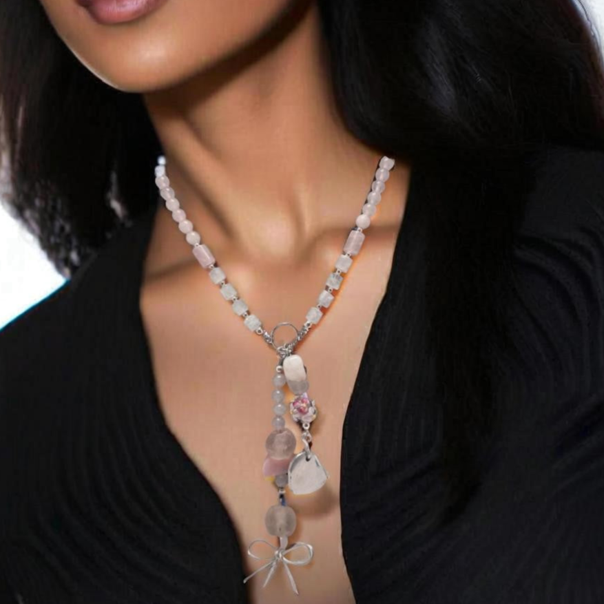 The Blush Bloom Y Necklace is a delicate, handcrafted piece featuring rose quartz, pink opal, sea glass, a floral lampwork bead, and a recycled aluminum heart. Designed with two Y-shaped pendants for a layered look, this 17.5-inch necklace embodies romance and sustainable elegance. Handmade in Canada. 