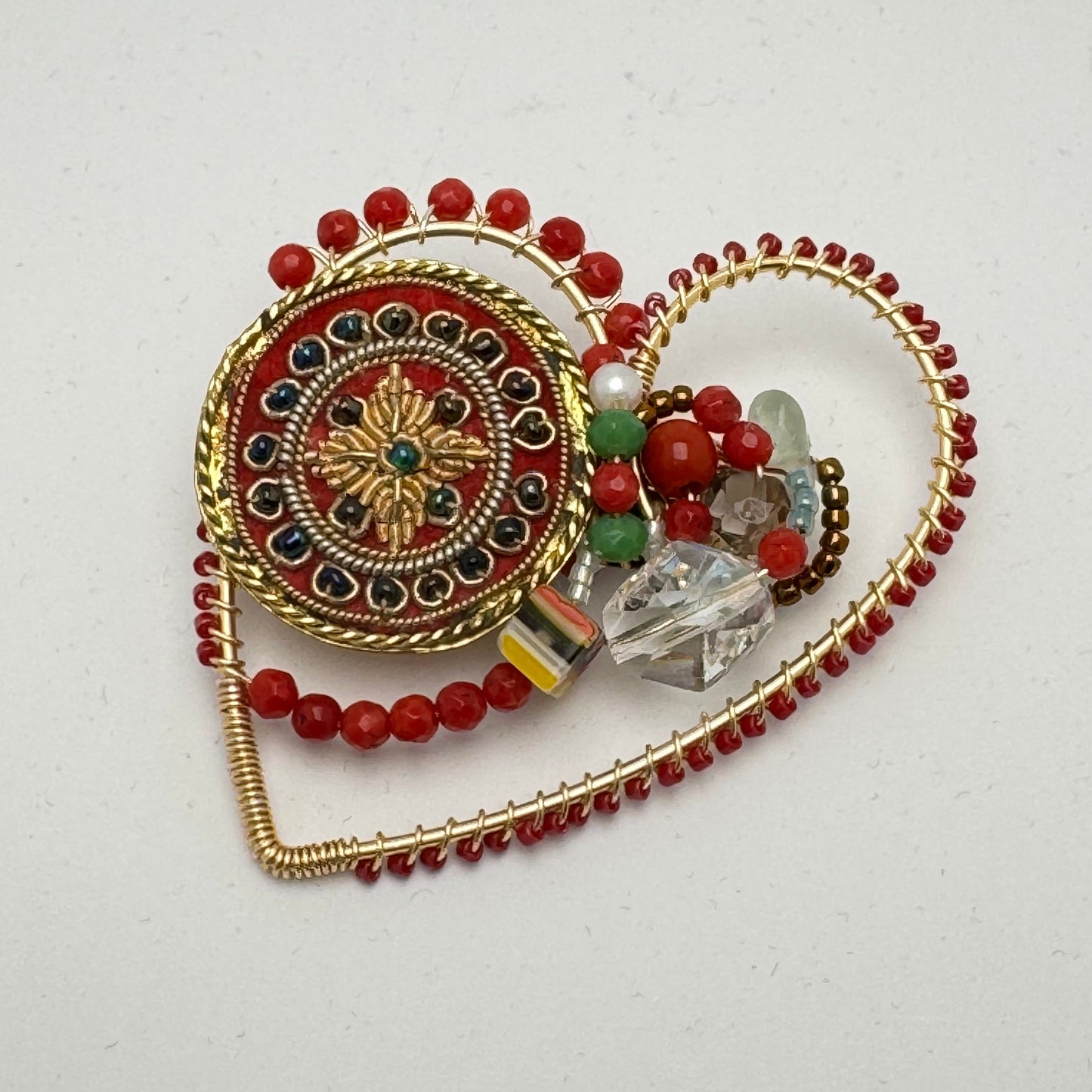 decorative heart shaped brooch with multicoloured semi precious and glass beads on a white background