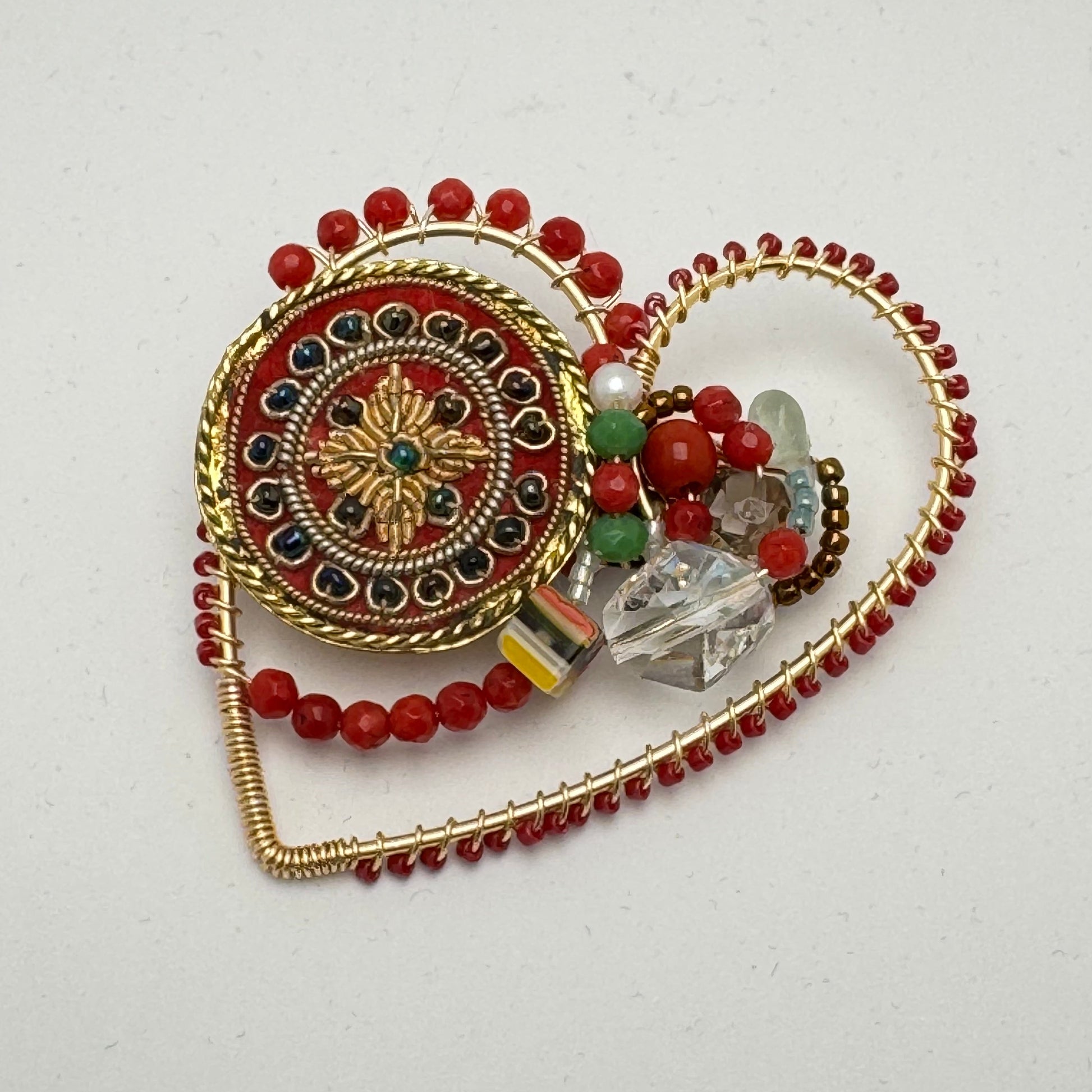 decorative heart shaped brooch with multicoloured semi precious and glass beads on a white background