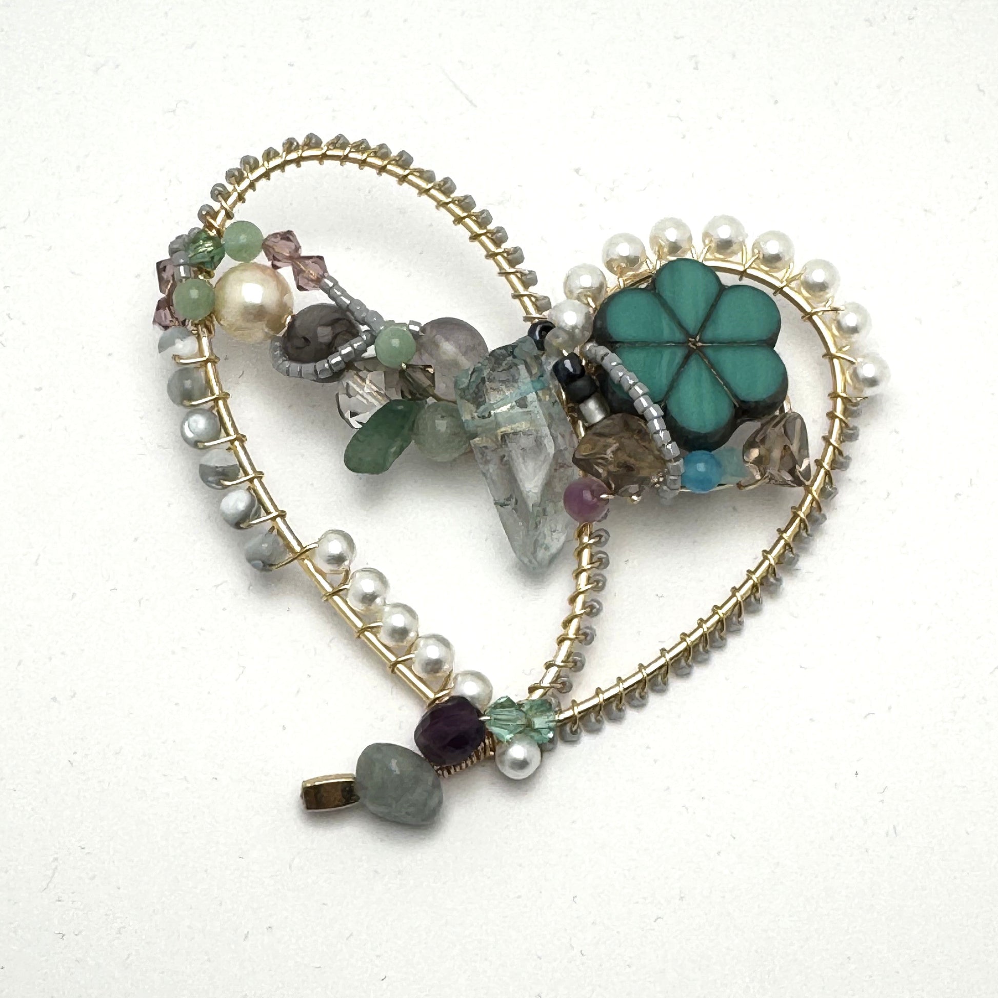 Heart-shaped jewelry piece with beads and a flower charm on a white background