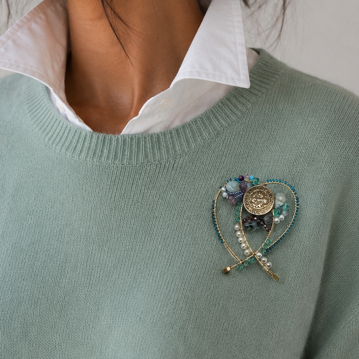woman wearing wire beaded brooch on sea green sweater.