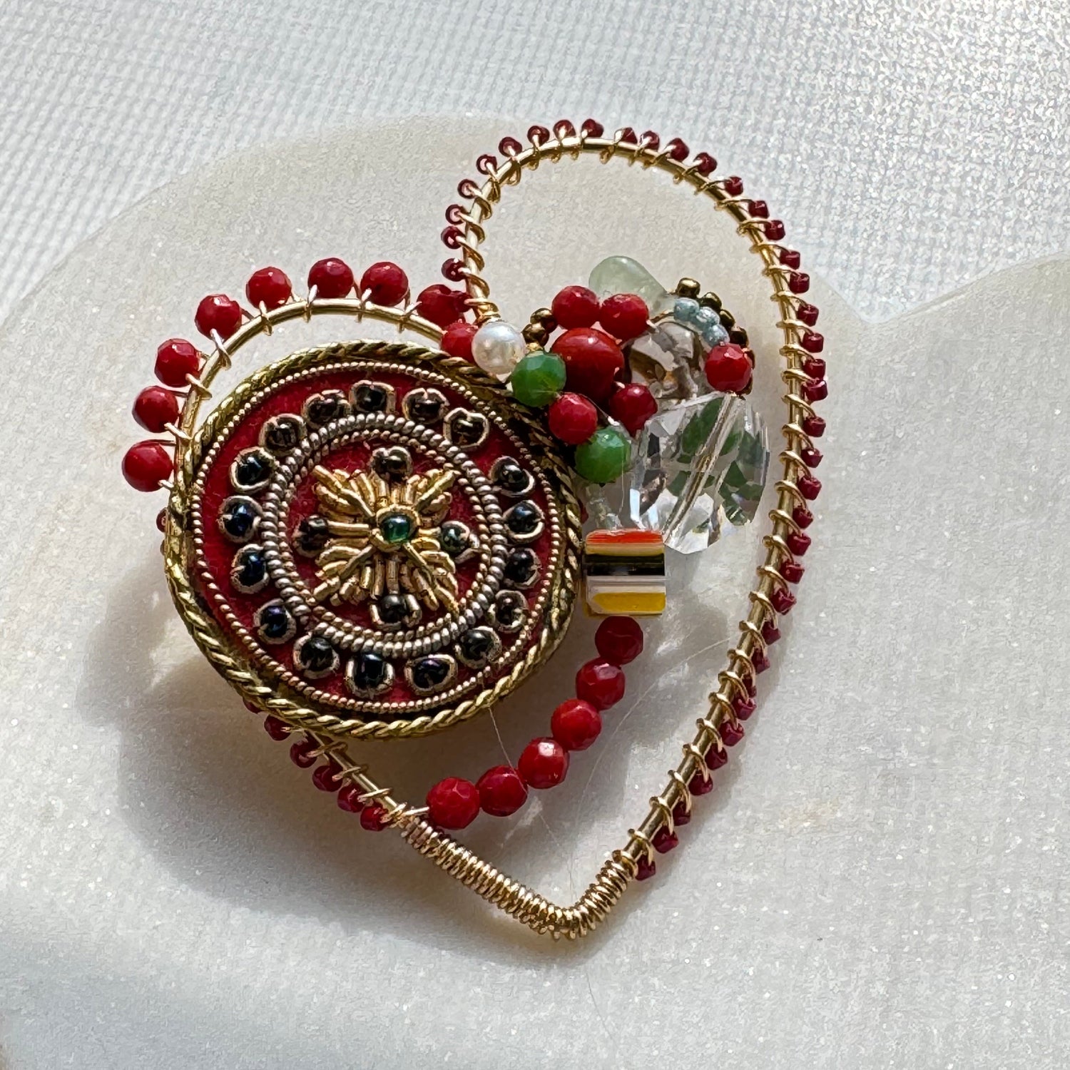Decorative brooch with red and gold details on a white background