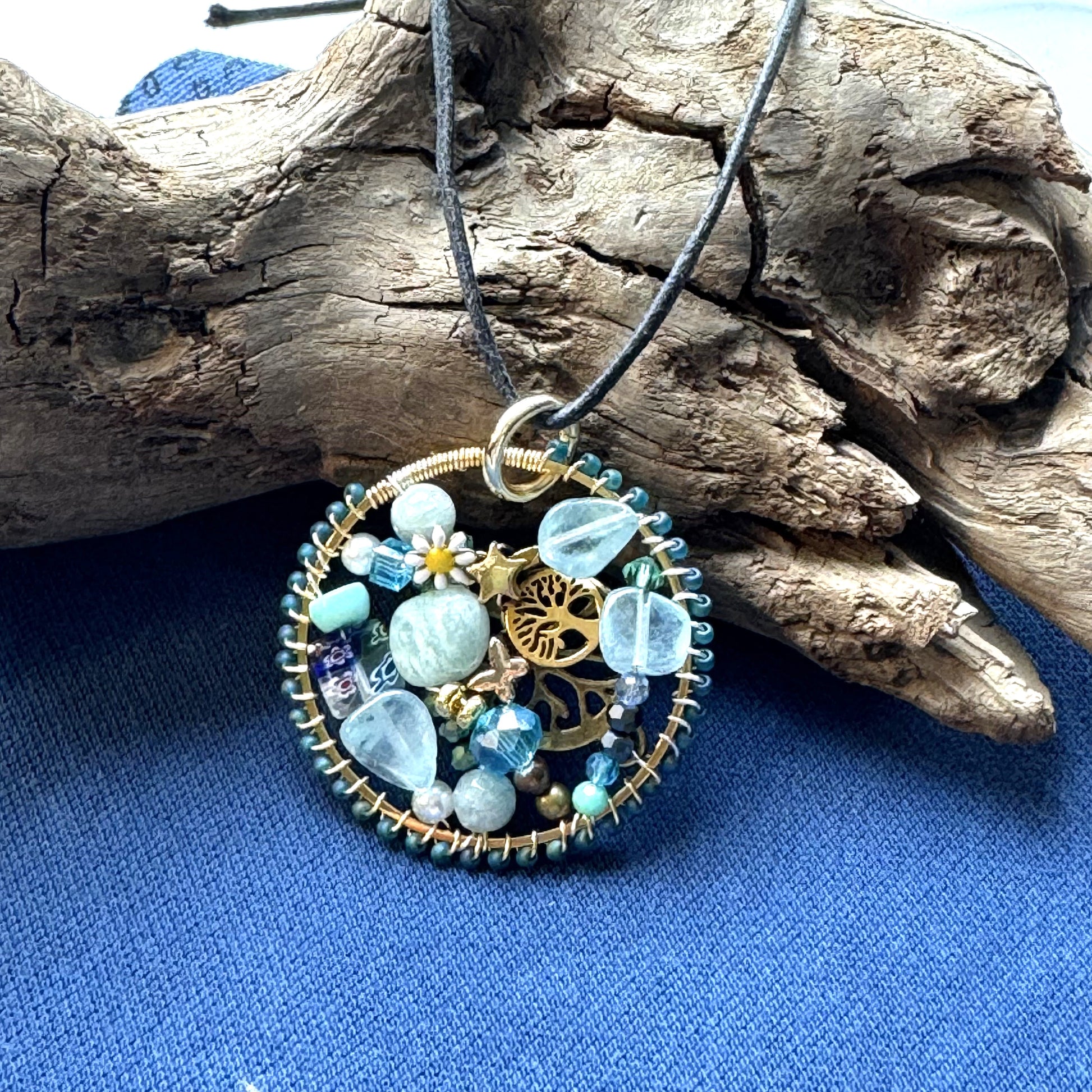 Handmade Halo pendant with aqua and turquoise stones, crystals, tree of life charm, and black cord necklace.