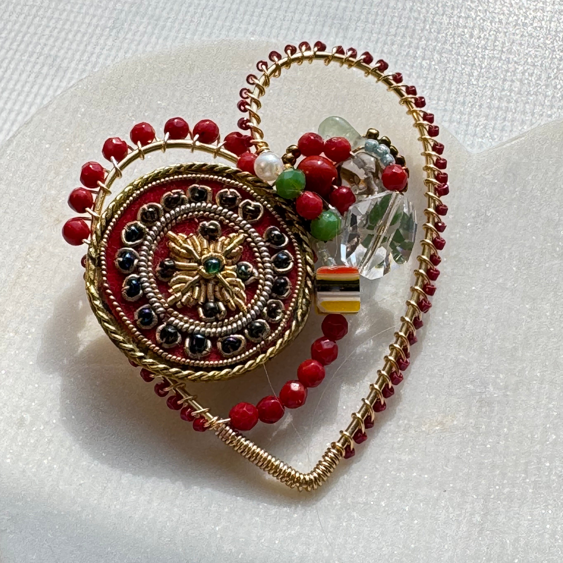 Decorative jewelry piece with red beads and gold accents on a white background