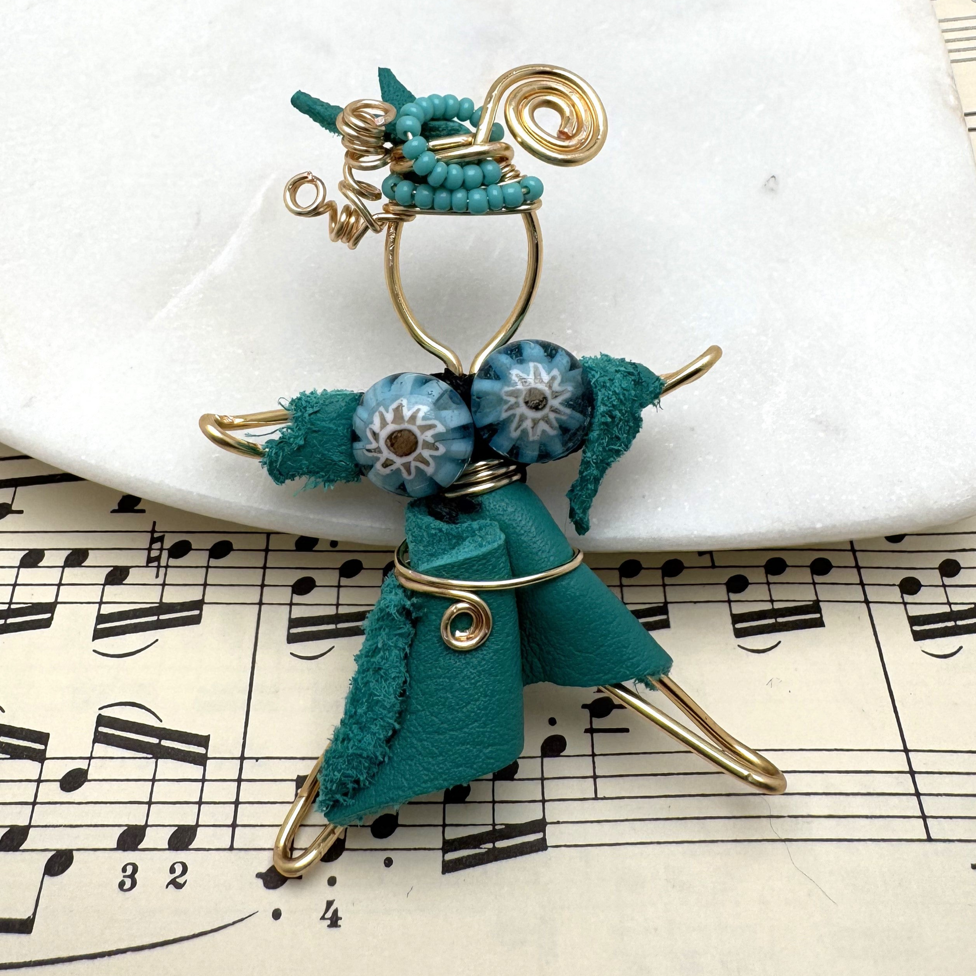 A handcrafted Pixie Pin brooch made from soft turquoise suede, featuring a whimsical design that embodies creativity and nature-inspired charm. Made in Canada with recycled materials.